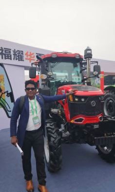 KCCIMA delegate beside a red tractor at an agricultural exhibition