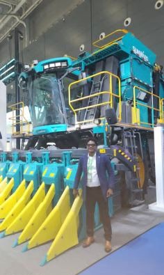 KCCIMA delegate standing in front of a large teal Sunward cotton harvester