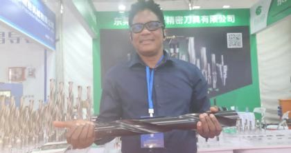 KCCIMA delegate holding a large precision drill bit at a cutting-tools exhibition stand